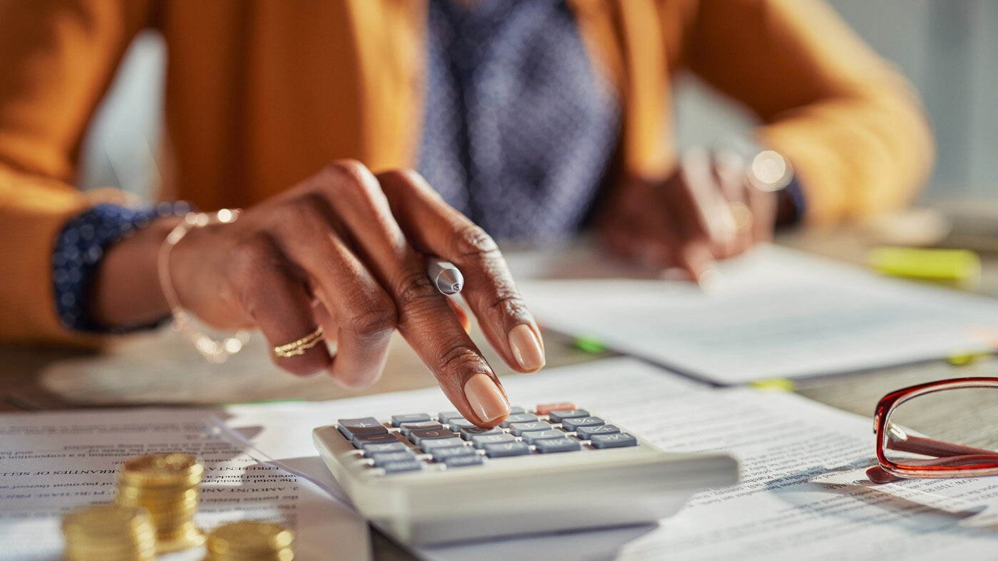 Person using a calculator for financial management with documents, representing C&D Advisory's tax compliance consulting.