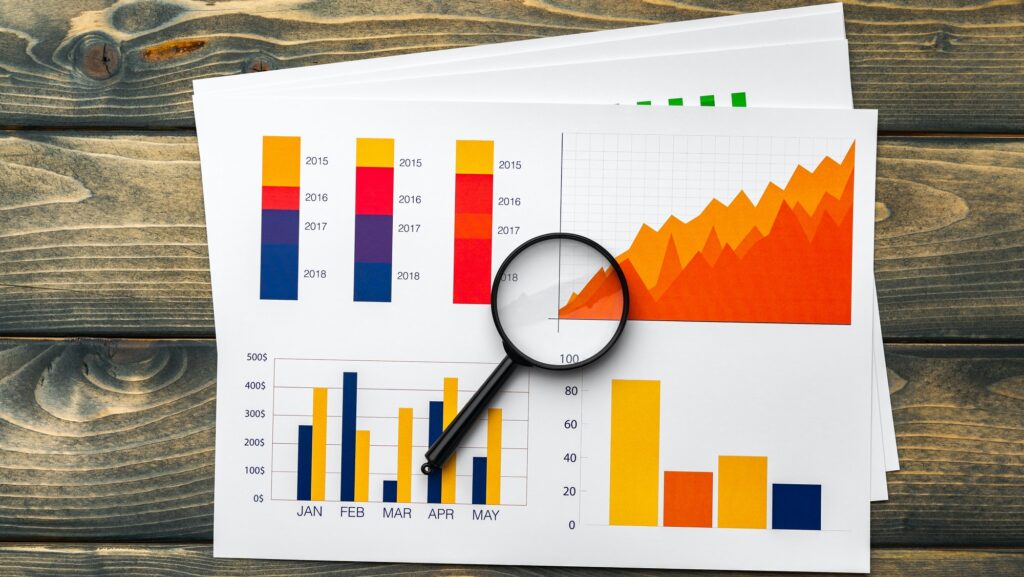 Business graphs and magnifying glass on table