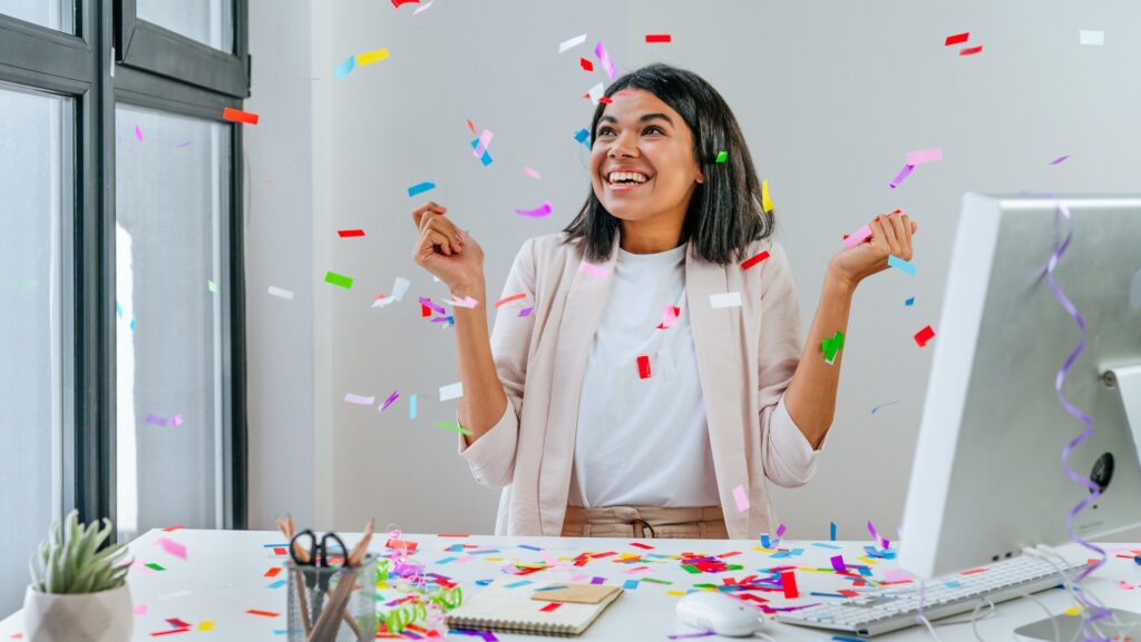 Young business woman having fun time catching confetti